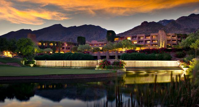 Long exposure of a luxury hotel resort. A golf course and pond is in the foreground and foothill mountains in the background.