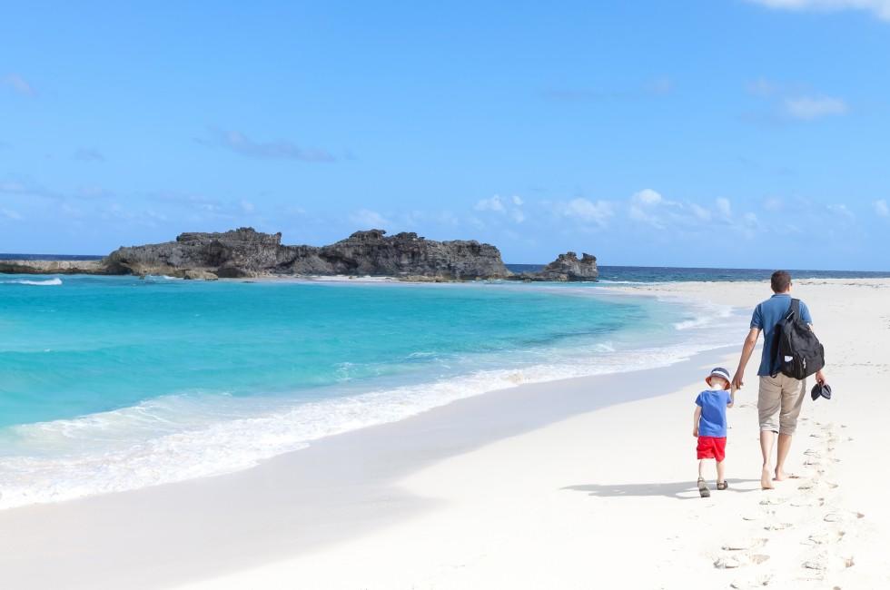 young father and his son walking at the perfect caribbean beach at middle caicos.