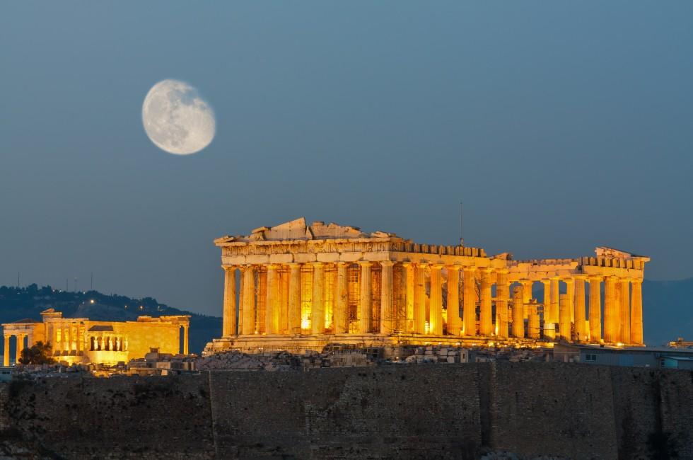 Parthenon construction in Acropolis Hill in Athens, Greece shot in blue hour with moon in the sky