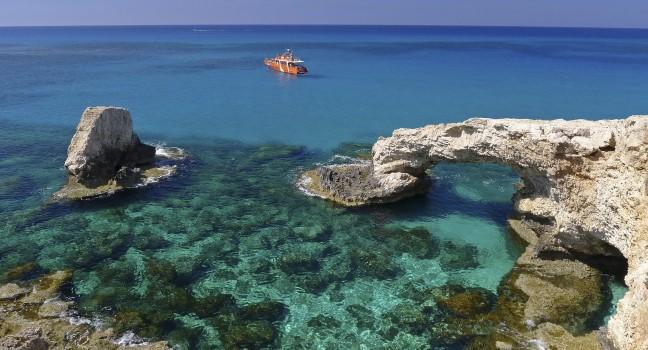 Emerald green sea water with rock arch on Cyprus island;