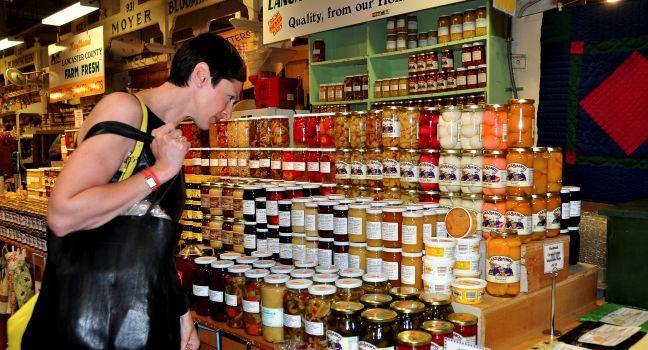 Woman shopping for delicious homemade preserves sold by an Amish family at the Reading Terminal Market in Philadelphia, Pennsylvania.